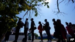 FILE - Migrants stand stand in line at a respite center after they crossed the U.S.-Mexico border and turned themselves in and were released in Del Rio, Texas, June 16, 2021.