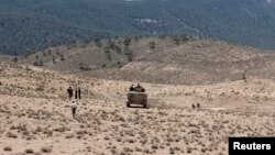 FILE - Tunisian soldiers patrol near the border with Algeria as seen from the area of Mount Chambi, west Tunisia, June 11, 2013.
