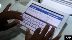 FILE PHOTO - A Cambodian man logs into Facebook as he inspects the iPad 2 during an Apple store opening in Phnom Penh on September 9, 2011. (Photo by TANG CHHIN SOTHY / AFP)