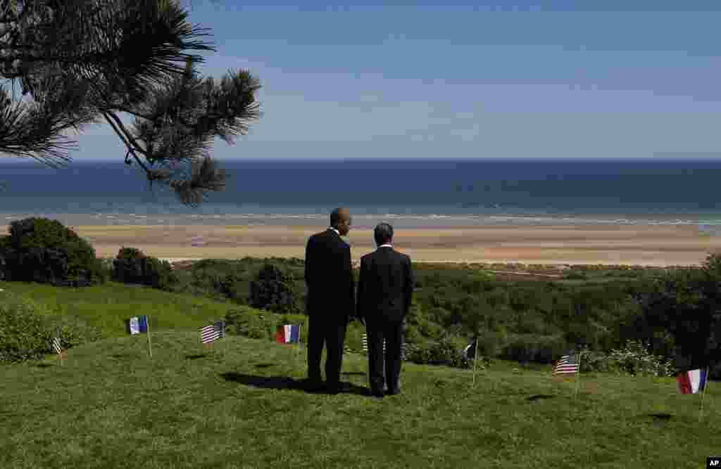 U.S. President Barack Obama and French President Francois Hollande look out at Omaha Beach, one of the sites of the Allied beach landings, at Normandy American Cemetery in Colleville sur Mer in Normandy, France, June 6, 2014.