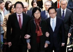 Selina Tsang, center, wife of former Hong Kong leader Donald Tsang, is accompanied by her two sons, Simon Tsang Hing-yin, left, and Thomas Tsang Hing-shun, to walk out of the High Court in Hong Kong, Feb. 22, 2017.