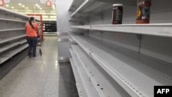 A woman walks between empty shelves of a supermarket in Caracas, Venezuela, Jan. 11, 2018. 