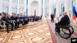 FILE - Sir Philip Craven, president of the International Paralympic Committee, right, speaks as Russian President Vladimir Putin, standing background center, listens to him during an awards ceremony in the Kremlin in Moscow, March 24, 2014.