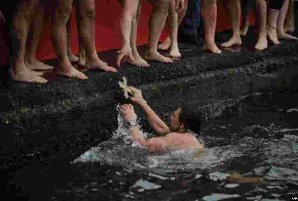 Greek Orthodox man Apostolis Oikomoniv holds the wooden cross after he retrieved it from the water during an Epiphany ceremony to bless the water in the Golden Horn in Istanbul, Turkey, Friday, Jan. 6, 2012. Similar ceremonies to mark Epiphany Day were h