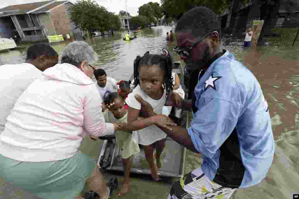 Une petite fille est secourue par les habitants alors que le niveau de l'eau a atteint 30 centimètres à Houston, Texas, 18 avril 2016.