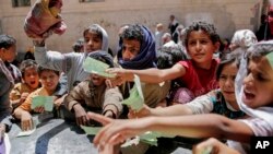 FILE - Yemenis present documents in order to receive food rations provided by a local charity, in Sanaa, Yemen, April 13, 2017.