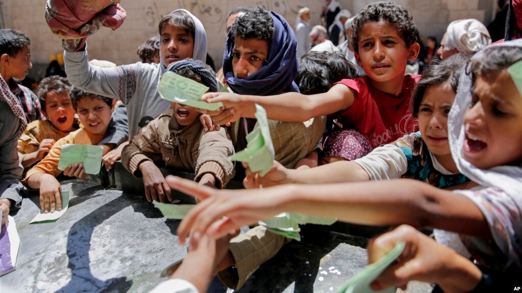 Yemeníes muestran sus tarjetas de identificación para poder recibir alimentos de una organización caritativa en Sanaa, Yemen, en abril de 2017.