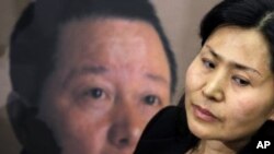 Geng He, wife of disappeared Chinese human rights lawyer Gao Zhisheng, seen on poster at rear, is interviewed before a news conference with Rep. Chris Smith, R-N.J., on Capitol Hill in Washington. (File Photo - January 18, 2011)