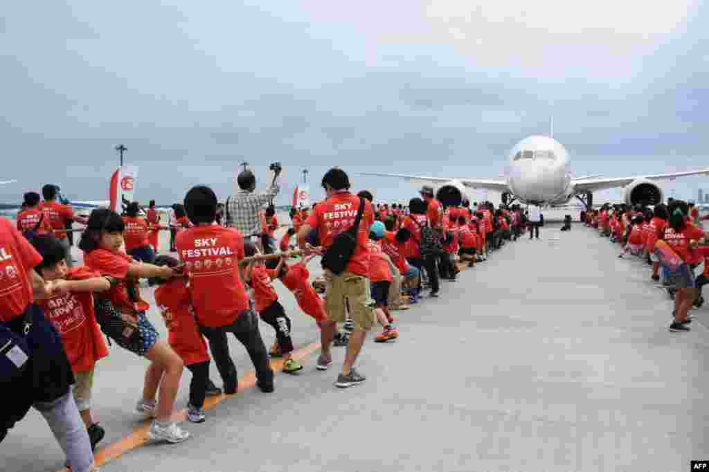 A 166 elementary school children and their 112 parents pull a Boeing 787 jetliner at the Narita International airport in Narita, suburb of Tokyo, Sept. 13, 2015.