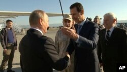 FILE - In a frame grab made available by Russian Presidential TV, Syrian President Bashar Assad, right, greets Russian President Vladimir Putin upon his arrival to the Hemeimeem air base in Syria, Dec. 11, 2017.