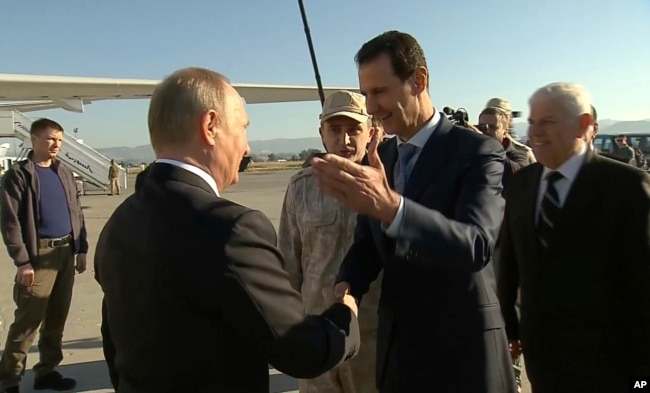 FILE - In a frame grab made available by Russian Presidential TV, Syrian President Bashar Assad, right, greets Russian President Vladimir Putin upon his arrival to the Hemeimeem air base in Syria, Dec. 11, 2017.