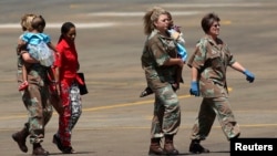 Members of the South African Army carry two children, who sustained injuries in a collapsed church guesthouse in Lagos and were evacuated from Nigeria, as they arrive at an air force base north of Johannesburg, Sept. 22 2014.