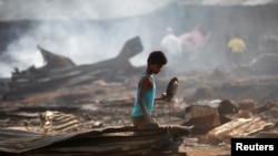 A boy searches for useful items among the ashes of burnt down dwellings after a fire destroyed shelters at a camp for internally displaced Rohingya Muslims in Myanmar's western Rakhine State near Sittwe, May 3, 2016.