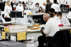 Petugas pemilihan Detroit bekerja menghitung surat suara yang tidak hadir untuk pemilihan umum 2020 di TCF Center pada 4 November 2020 di Detroit, Michigan. (Foto: AFP)