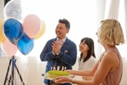 FILE - Marie Kondo, center, looks on as a cake is brought to celebrate her husband Takumi Kawahara's birthday in New York, Wednesday, July 11, 2018. (AP Photo/Seth Wenig)