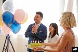 FILE - Marie Kondo, center, looks on as a cake is brought to celebrate her husband Takumi Kawahara's birthday in New York, Wednesday, July 11, 2018. (AP Photo/Seth Wenig)