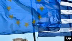 Bendera Uni Eropa dan Yunani berkibar di depan Acropolis, pusat kota Athena (Foto: dok). IMF, Bank Sentral Eropa dan Komisi Eropa akan mengeluarkan dana talangan $3,7 miliar untuk Yunani dalam waktu dekat.