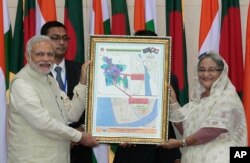 FILE - Bangladesh’s Prime Minister Sheikh Hasina and Indian Prime Minister Narendra Modi hold a location map of Indian Economic Zones during an agreement program in Dhaka, Bangladesh, June 6, 2015.
