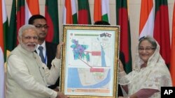 Bangladesh’s Prime Minister Sheikh Hasina, right, and Indian Prime Minister Narendra Modi hold a location map of Indian Economic Zones during an agreement program in Dhaka, Bangladesh, June 6, 2015.