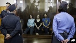 Feminist punk group Pussy Riot members, from left, Yekaterina Samutsevich, Maria Alekhina and Nadezhda Tolokonnikova sit in a glass cage at a courtroom in Moscow, Russia, Aug 17, 2012.