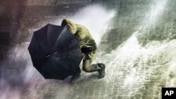 A man uses an umbrella as Turkish riot police fire water cannons and tear gas at hundreds of demonstrators who try to march to Taksim Square in Istanbul, Feb. 8, 2014.