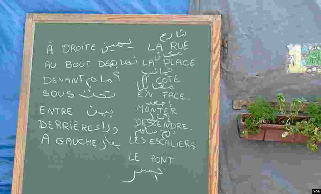 Words in Arabic and French are seen on a chalk board at a migrant school in the Jungle camp in Calais, France. (L. Bryant/VOA)