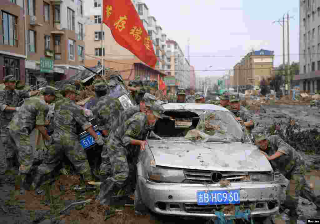 Rescue workers drag damaged cars out of debris and mud after a flood in Yongji, Jilin province, China.