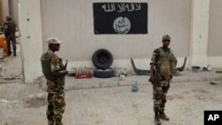 FILE - Soldiers stand at a checkpoint in front of a Boko Haram flag the Nigerian city of Damasak, Nigeria, March 18, 2015. 