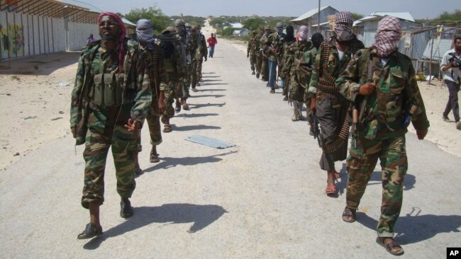 FILE - Members of Somalia's al-Shabab militant group patrol on foot on the outskirts of Mogadishu, March 5, 2012. Somalia now says al-Shabab militants are plotting to supply uranium to Iran.