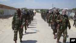 FILE - Members of Somalia's al-Shabab militant group patrol on foot on the outskirts of Mogadishu, Somalia, March 5, 2012. 