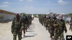 FILE - members of Somalia's al-Shabab militant group patrol on foot on the outskirts of Mogadishu, Somalia, March 5, 2012. Somalia now says says al-Shabab militants are plotting to supply uranium to Iran.