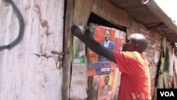 Eleitora queniano colando posters de campanha no bairro de Kibera, em Nairobi (Arquivo)