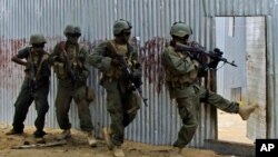 Masked Somali national army (SNA) soldiers search through homes for al-Shabaab fighters, during an operation in Ealsha Biyaha, Somalia, Saturday, June, 2, 2012.