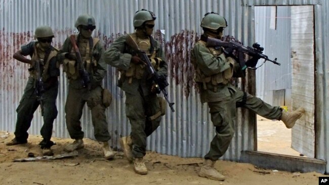 FILE - Masked Somali national army (SNA) soldiers search through homes for al-Shabab fighters, during an operation in Ealsha Biyaha, Somalia, June, 2, 2012.