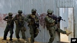 Masked Somali national army (SNA) soldiers search through homes for al-Shabaab fighters, during an operation in Ealsha Biyaha, Somalia, Saturday, June, 2, 2012.