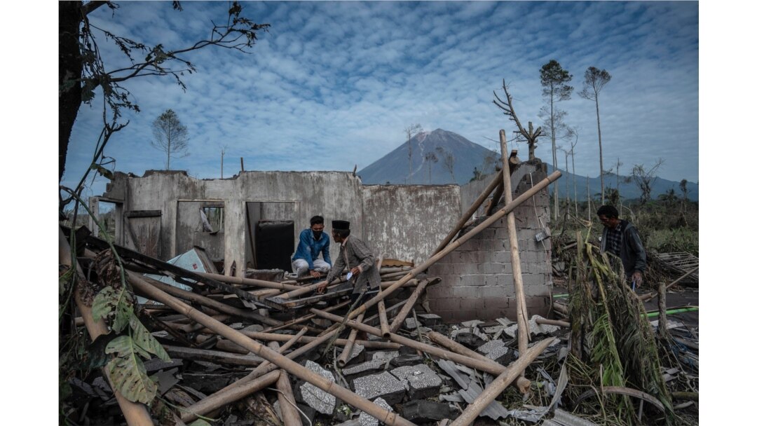 Penduduk desa menyelamatkan barang-barang mereka dari rumah mereka yang rusak di Desa Curah Kobokan di Lumajang pada 8 Desember 2021, setelah letusan gunung berapi Gunung Semeru yang menewaskan sedikitnya 34 orang. (Foto: AFP)