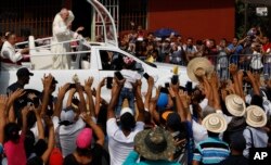 Residents line the roadside to greet Pope Francis as he rides past in his popemobile en route to Las Garzas de Pacora detention center for minors, in Panama, Jan. 25, 2019.