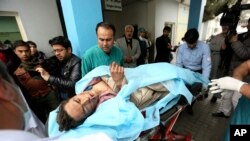 FILE - Afghans help an injured man at a hospital after a suicide attack, in Kabul, Nov. 21, 2016. 