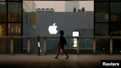 FILE - A woman walks past an Apple store in Beijing, China, July 28, 2016. 