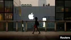 FILE - A woman walks past an Apple store in Beijing, China, July 28, 2016. 