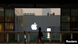 FILE - A woman walks past an Apple store in Beijing, China, July 28, 2016. 