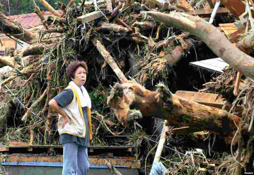 A woman reacts in front of collapsed houses following a landslide caused by Typhoon Wipha on Izu Oshima island, south of Tokyo, in this photo taken by Kyodo, Oct. 16, 2013.