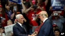 El vicepresidente Mike Pence, (izquierda) saluda al presidente Donald Trump en el escenario durante un acto de campaña el jueves, 10 de mayo, de 2018, en Elkhart, Indiana.