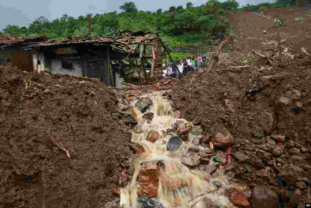 Warga desa menonton operasi penyelamatan lokasi tanah longsor yang menimpa keseluruhan wilayah desa Malin, di negara bagian Maharashtra, India Barat. Hujan lebat menghambat upaya para petugas penyelamat melakukan penggalian lumpur tebal dan puing-puing, sementara korban yang meninggal telah melampaui 50 orang. &nbsp;