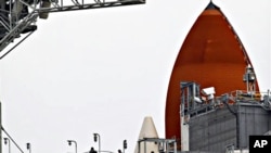 NASA workers walk near the external tank, rear, of the space shuttle Discovery at the Kennedy Space Center in Cape Canaveral, Florida, February 23, 2011