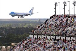 Aficionados a las carreras de automóviles observan desde las gradas cuando el avión Air Force One da una vuelta sobre el circuito Daytona mientras el presidente Donald Trump llega para asistir a la carrera de autos NASCAR Daytona 500 en Daytona Beach, Florida, el 16 de febrero de 2020.