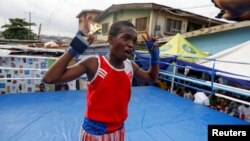 Boxer Tijani Abdulazeez, popularly known as TJ, 15, poses with his trophy after winning at the youth tournament in Iyana-ipaja, Lagos, Nigeria. (REUTERS/Temilade Adelaja)
