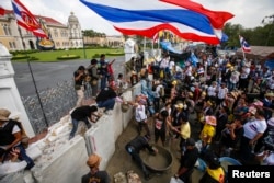 Anti-government protesters mix cement to be used for building a wall to block a gate of the Government House during a rally in Bangkok, Feb. 17, 2014.