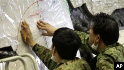 Japan's Defense Ministry officials plot possibly radioactive affected areas on a map at the emergency rescue headquarters monitoring leaked radiation from the Fukushima nuclear facilities, Fukushima city, Fukushima prefecture, Japan, March 16, 2011