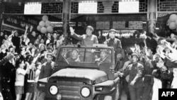 历史照片：毛泽东（1893-1976）和林彪（1907-1971）在敞篷吉普车上向在北京天安门广场庆祝五一节的群众挥手致意。（1967年5月1日）